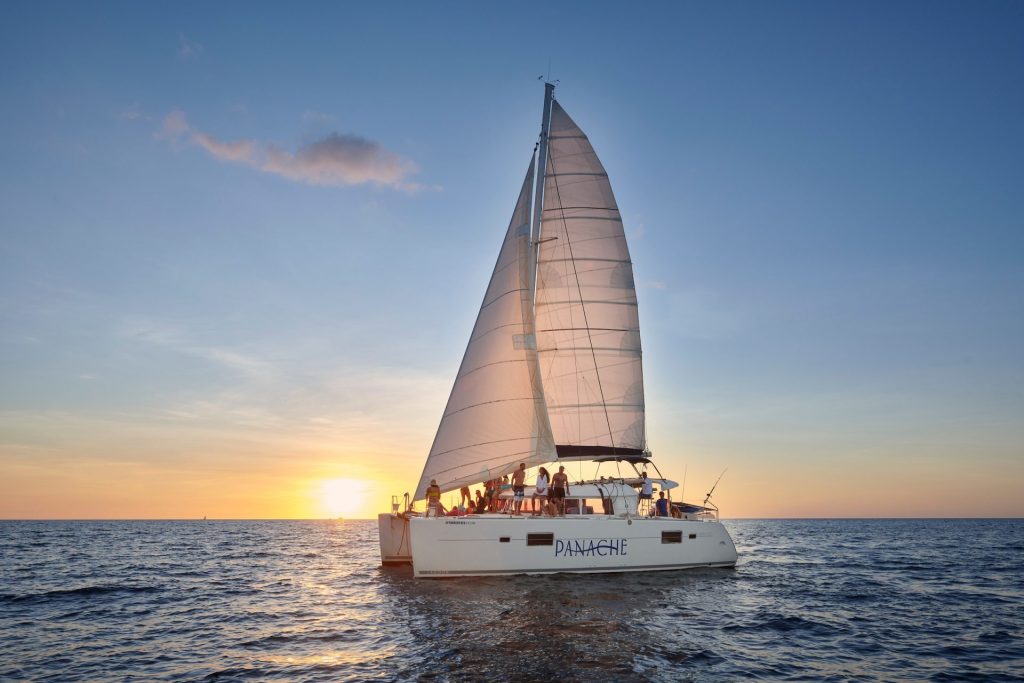 Catamaran sailing at sunset.