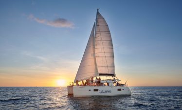 Catamaran sailing at sunset.