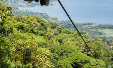 Aerial tram over lush green landscape.