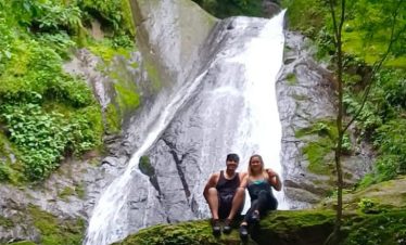 Couple sitting by a waterfall.