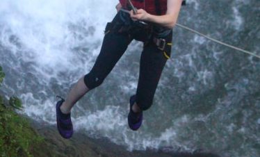 Person rappelling down a waterfall