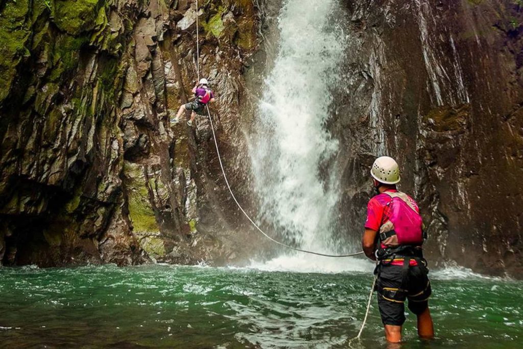 Climbers near a waterfall's edge.
