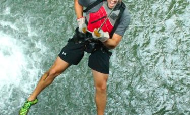 Person rappelling down a waterfall.