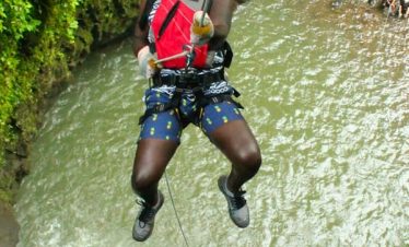 Person rappelling near a waterfall.