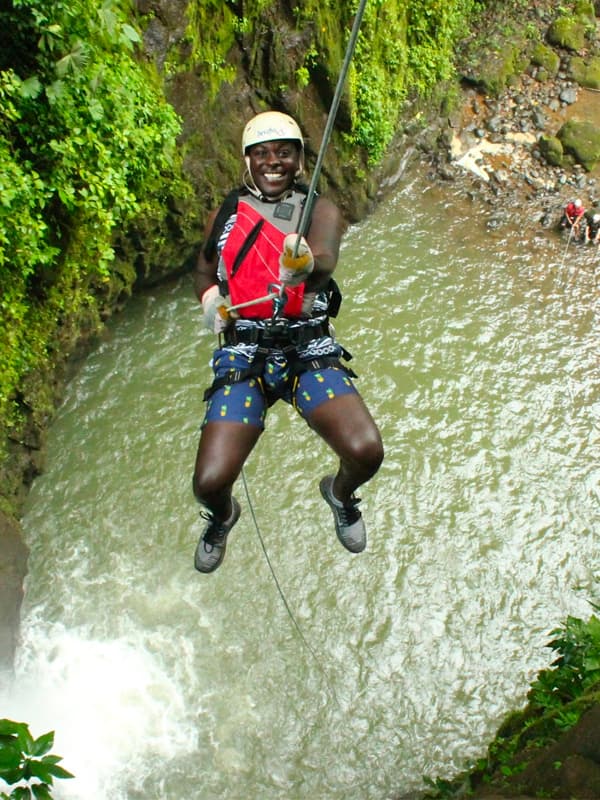 Person rappelling near a waterfall.