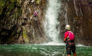 Climbers near a waterfall's edge.