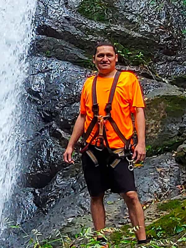 Person near waterfall wearing harness