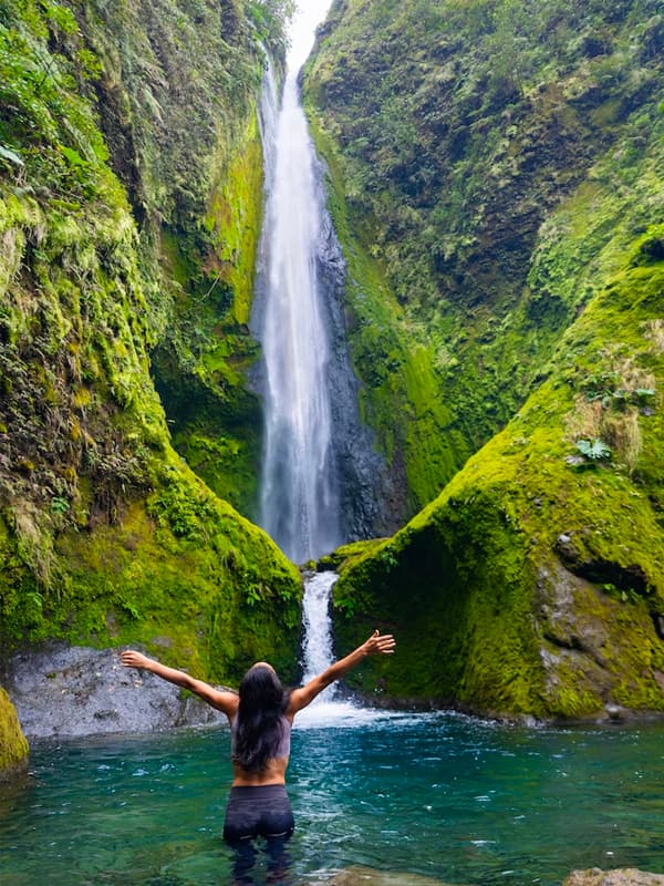 Person embracing nature by waterfall.