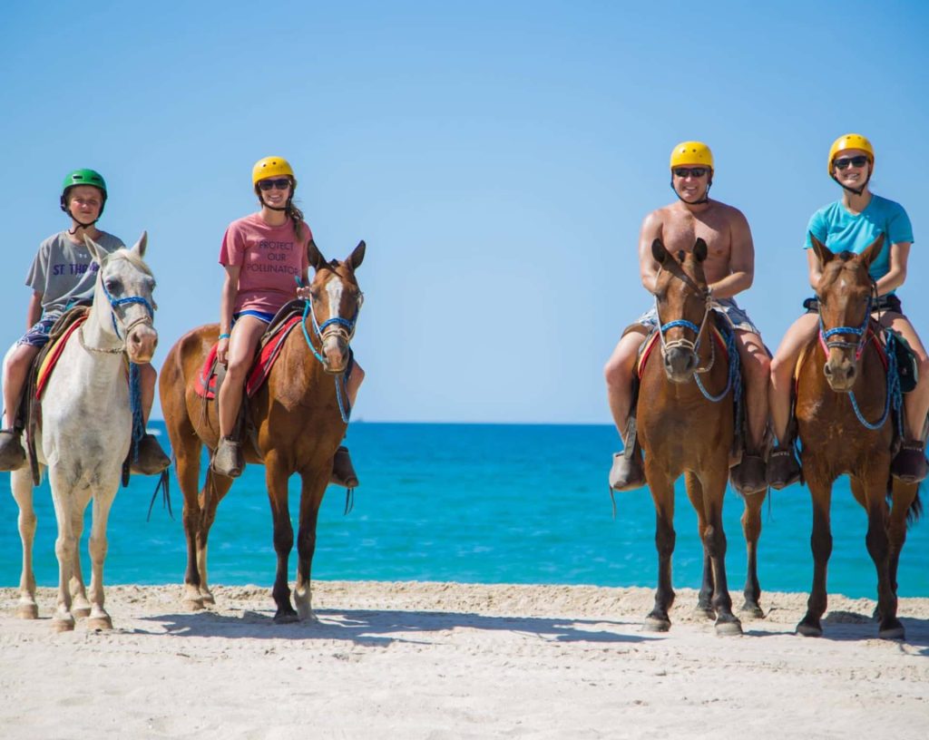People riding horses on the beach.