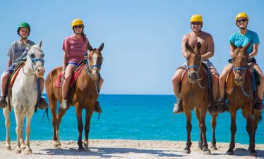 People riding horses on the beach.