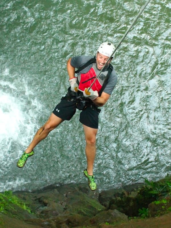 Person rappelling down a waterfall.