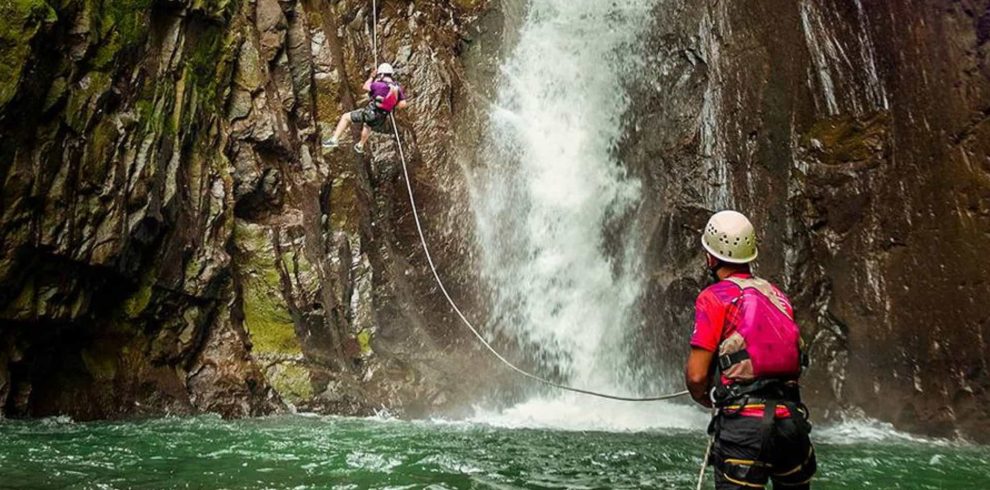 Climbers near a waterfall's edge.