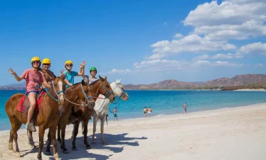 People horseback riding on the beach.