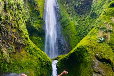 Person embracing nature by waterfall.
