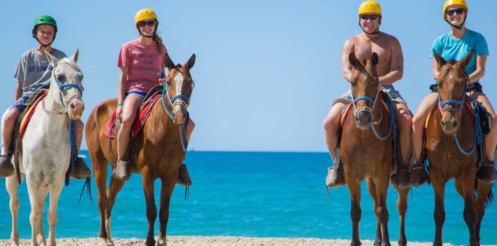 People riding horses on the beach.