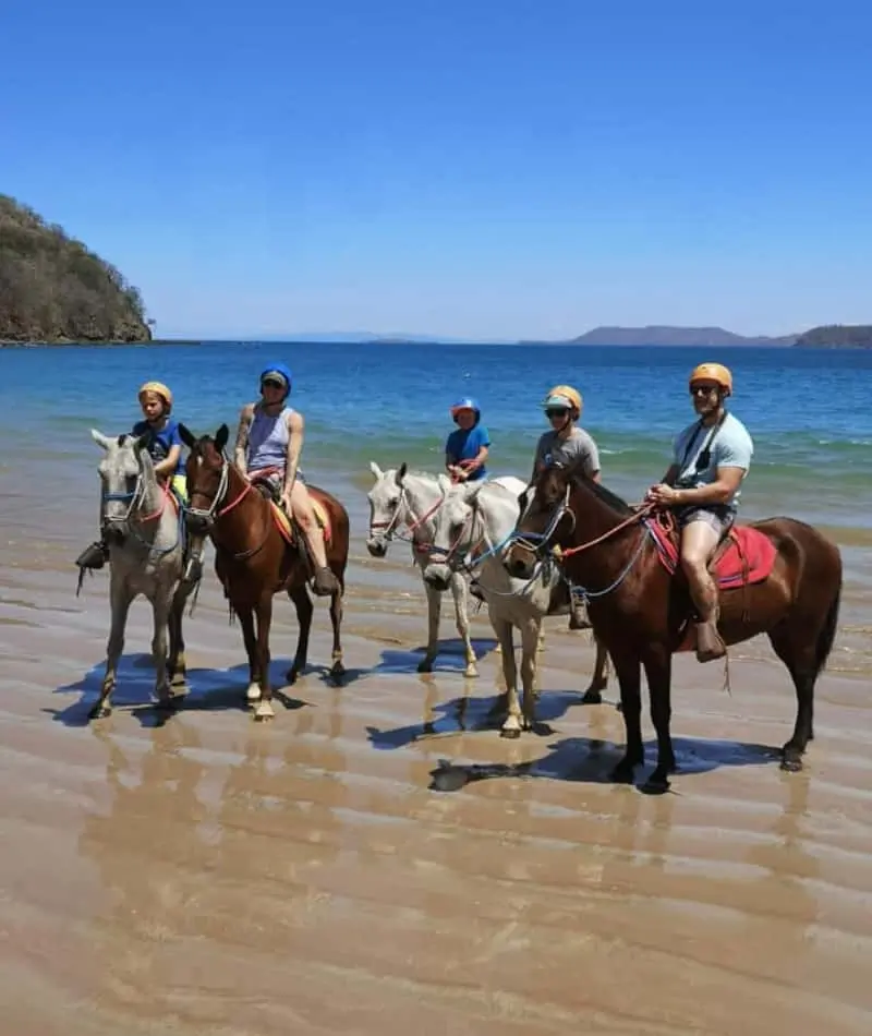 Group horseback riding on the beach.