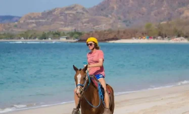 Person riding horse on beach